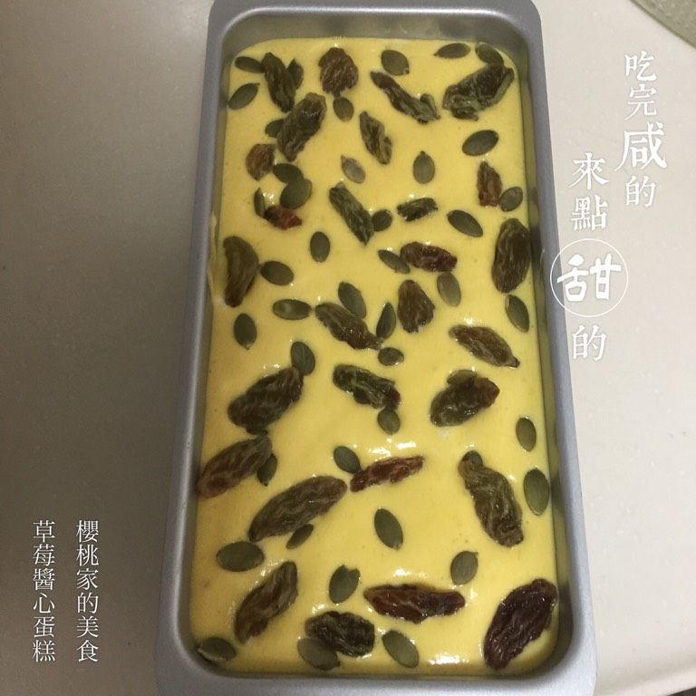 草莓酱心蛋糕,如图将另一半蛋糕糊倒入模具,表面撒上南瓜子和葡萄干;