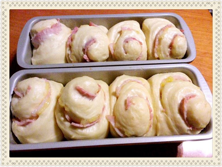 芝士培根吐司,将面团用面粉棍碾压成10*20长放型，放上培根、芝士粒，卷起成小卷，在中间切开二半（共16份，要4个吐司盒），放入吐司盒发酵1小时。入烤箱前涂上蛋浆。