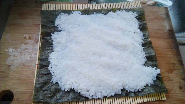 食寿司卷——剩米饭的华丽转身,在寿司帘上放上寿司<a style='color:red;display:inline-block;' href='/shicai/ 273'>紫菜</a>,将米饭铺平,不要压饭粒,尽量保持饭粒完整,松软,四周稍微留一点边。