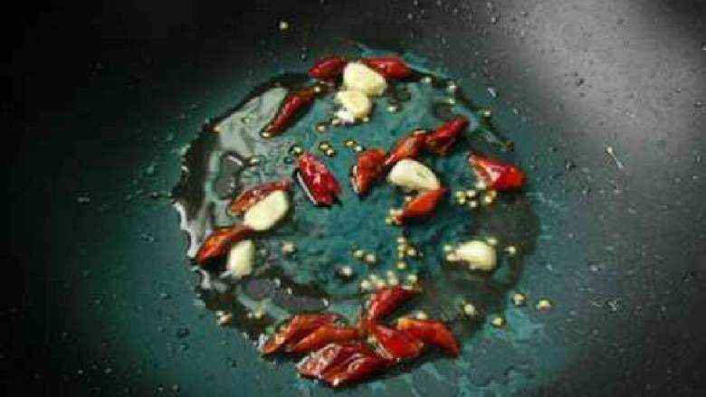 五花肉炒四季豆, 锅中留适量油，加入干辣椒段和蒜片炒出香味。