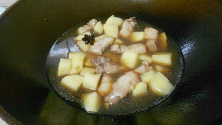 土豆炖五花肉,放入半碗水,放入酱油,中火,盖上盖子,慢慢炖煮