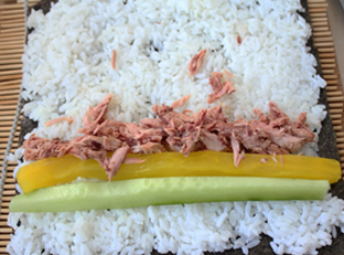金枪鱼紫菜包饭,寿司紫菜上铺上<a style='color:red;display:inline-block;' href='/shicai/ 507'>米饭</a>，靠下部摆上萝卜，黄瓜和金枪鱼罐头