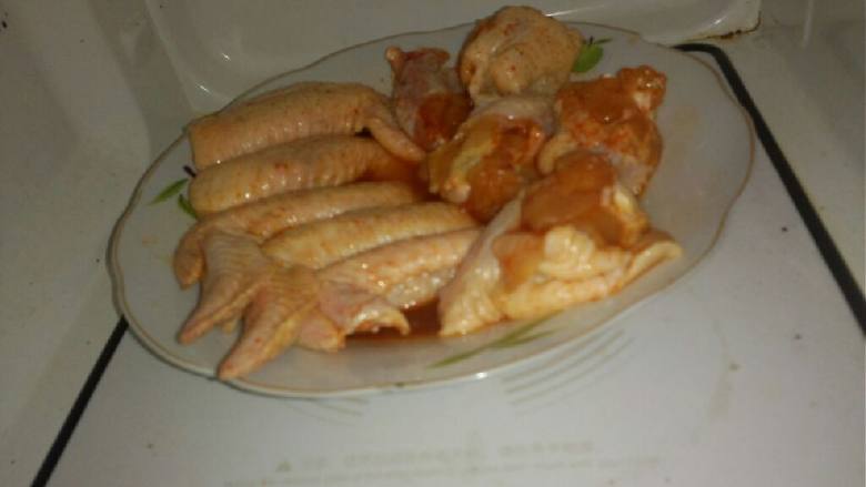 奥尔良鸡翅,腌好后在拿出来摆在盘里 倒入少许汤汁在鸡翅面上  在放入微波炉'烤七分钟