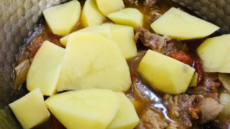 红焖牛肉煲,待牛肉烧至差不多时放入土豆,继续烧至土豆软烂即可。