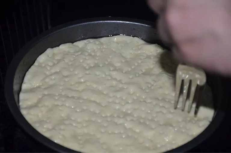牛肉披萨,将准备好的披萨皮材料混合一起和成面团,发2小时后擀成圆饼,放入抹油的披萨盘内,从中间向边远推开,边缘厚、中间薄,用西餐叉刺出小孔,如图。