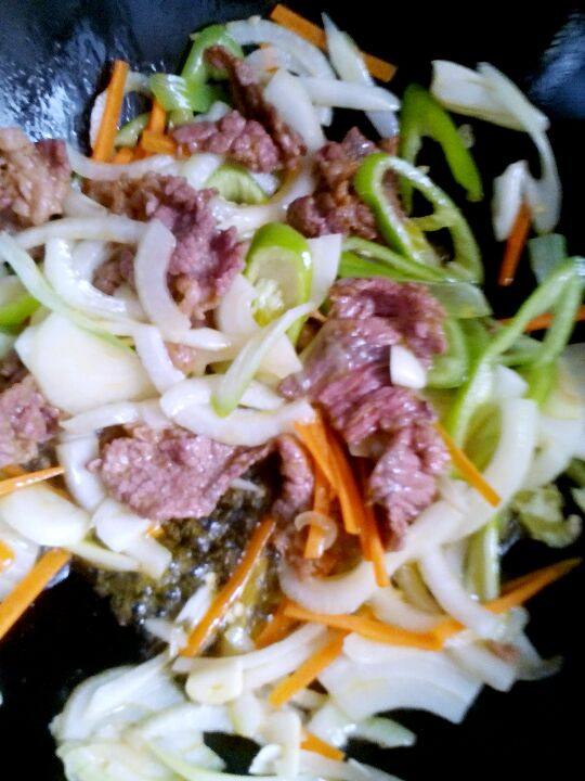 牛肉炒粉条,锅中加入适量的油， 有热后加入肉， 炒至变色，后加入蔬菜，炒几下。