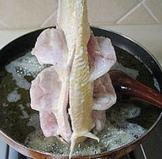 糖醋黄鱼,下八成热的油锅炸,先用手拿着鱼尾巴,用勺子将油缓慢的浇在鱼两边的花刀上