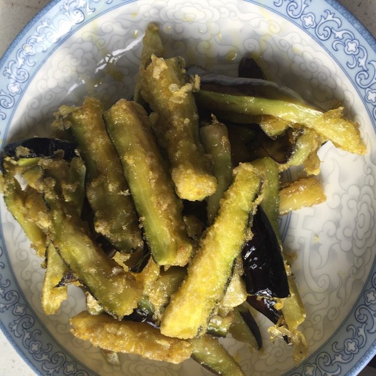 咸鱼茄子煲,茄子洒上少许淀粉,但要尽量让每一条茄白都有淀粉,然后用热油稍微炸一下,微微发黄即捞起备用。