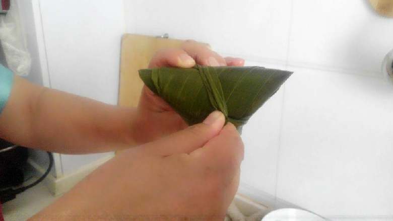 豆沙蜜豆粽子,一直包成右图的样子,然后把两条细叶子拧一块掖在里面