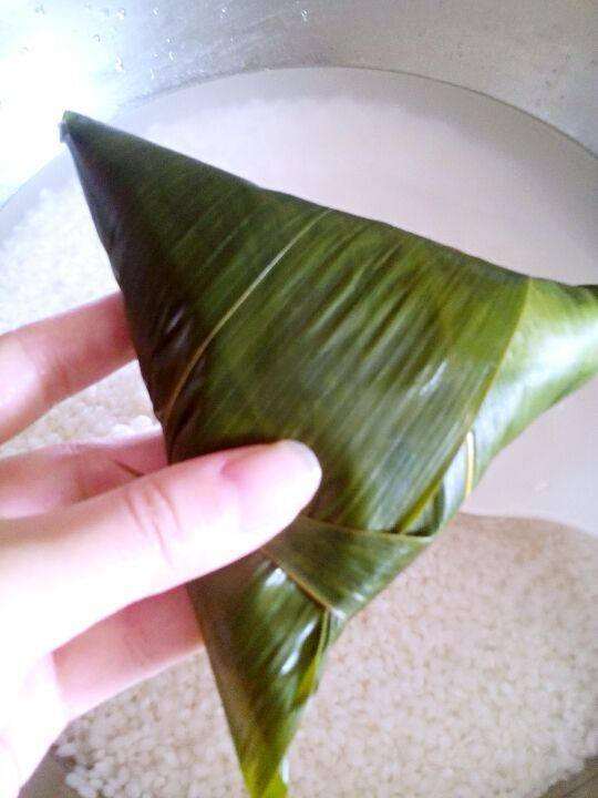 蜜枣粽子,然后再次加入米, 快满的的时候,灌入水,会自然流出后,粽子米会更紧实。按三角形卷起,如图。