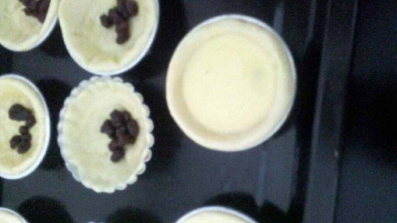 红豆蛋挞,挞水倒进挞皮中，8分满，烤箱预热200度，中层烤20分钟，出烤箱后撒上剩下的红豆在表面 装饰