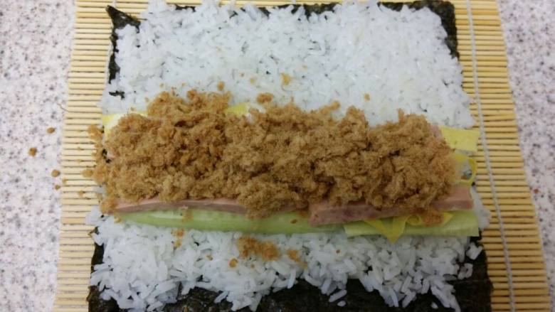 紫菜包饭,在靠自己的这一头，铺上黄瓜、鸡蛋、火腿、<a style='color:red;display:inline-block;' href='/shicai/ 432'>肉松</a>