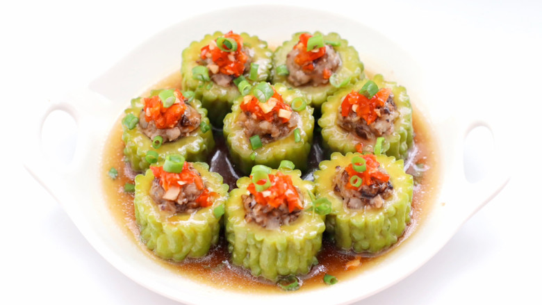 三伏天必备的苦瓜酿肉,取出把盘中汤汁倒入锅中,加入1勺蒸鱼豉油和少许水淀粉烧开,苦瓜上面码点剁椒酱和葱叶,浇上汤汁即可。
