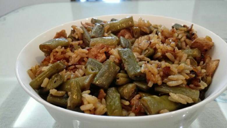 豆角鸡肉焖饭,将米和热水加入电饭锅中,倒入炒好的豆角鸡丁。启动菜饭功能,停止后焖十分钟,即可出锅。