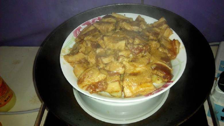 土豆粉蒸肉,将腌制好的肉块平铺在上面。记住:一定要平铺,不可摞堆在一起,平铺才会使食材受热均匀。开始蒸20分钟