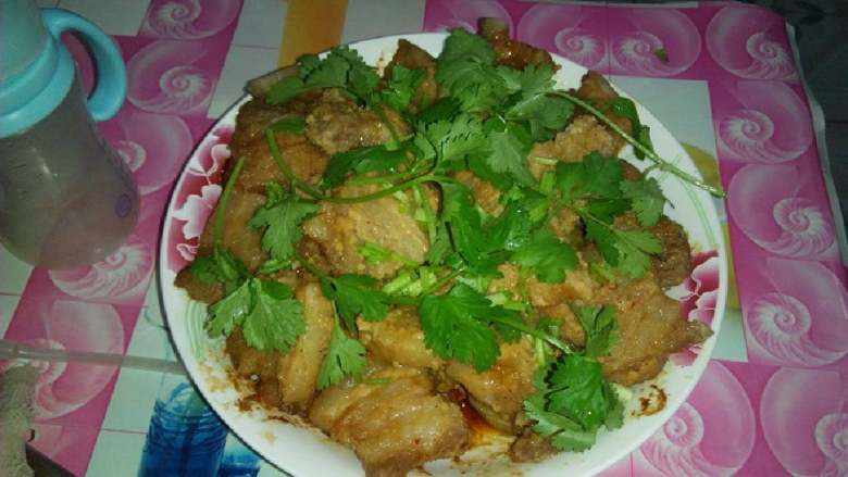 土豆粉蒸肉,上面铺上香菜,热气盖过香菜味道散发出来,很好吃哦。吃一口很回味。