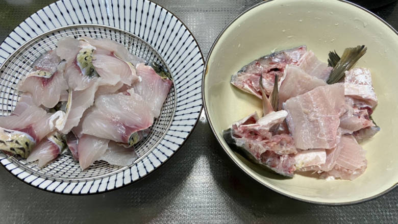 金汤鱼,鱼骨剁成块,清洗干净沥水备用。
鱼肉片成四五毫米厚的鱼片,不要切的太薄,草鱼肉太薄煮出来容易碎。清水中加入食盐,加入鱼肉抓洗几遍,洗去血水用厨房纸巾吸去表面水分