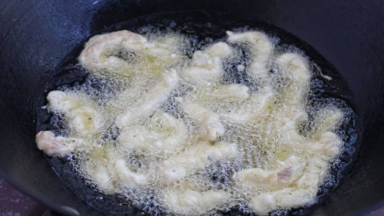 柠檬鸡柳,锅中倒入适量食用油烧至七八成热,改中小火一根一根地下入鸡肉条,炸至定型后再翻动,捞出控油。