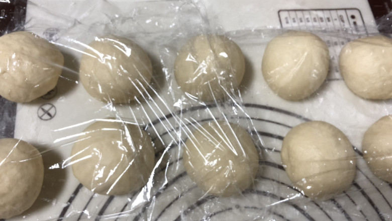 肉松肠仔包,发酵好的面团排一下面团中的气泡,均匀分割成十份,整形揉圆盖保鲜膜松弛10分钟。