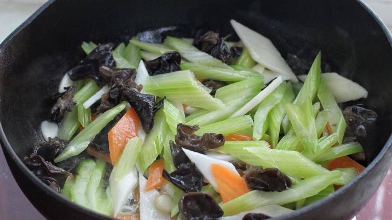 杂炒蔬菜,另起锅倒入适量食用油烧至五成热,下入蒜片小火炒香,接着将木耳、西芹、山药和胡萝卜一起放入锅中,改大火快速翻炒一分钟。