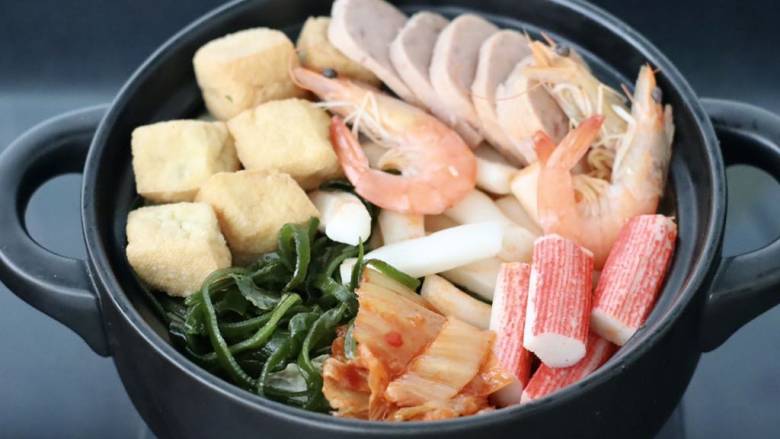 韩式年糕部队火锅,锅底平铺油豆腐和午餐肉,虾和蟹棒,<a style='color:red;display:inline-block;' href='/shicai/ 4872'>海带丝</a>和年糕条。
