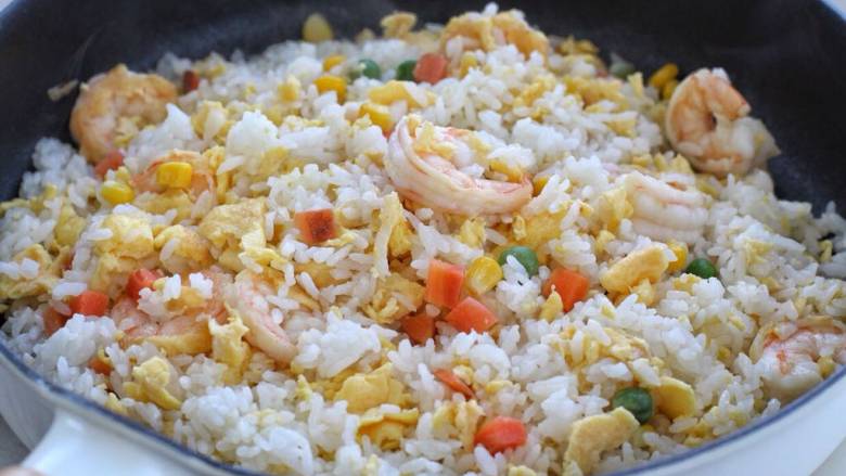 玉米虾仁蛋炒饭,接着倒入米饭开中火翻炒捣散,再放入玉米粒杂蔬混合翻炒均匀。