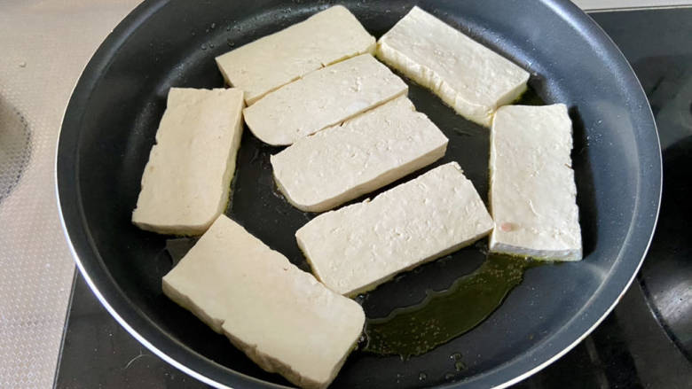 椒盐豆腐,平底锅加适量食用油,油温六成热,摆入豆腐片,中火煎