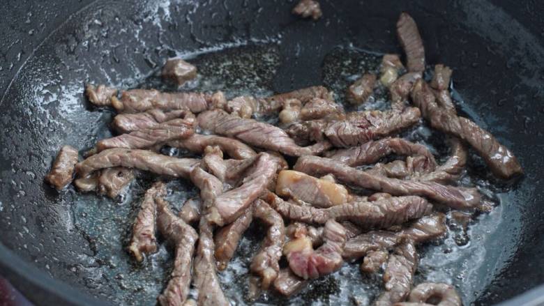 青椒爆炒牛里脊,锅中倒适量食用油,下入腌制好的牛肉条快速翻炒变色断生盛出。