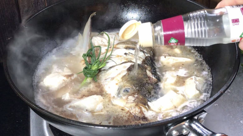 鱼头炖汤,接着加入盐、胡椒粉和料酒,煮沸后继续煮2分钟,再盖上盖子煮10分钟