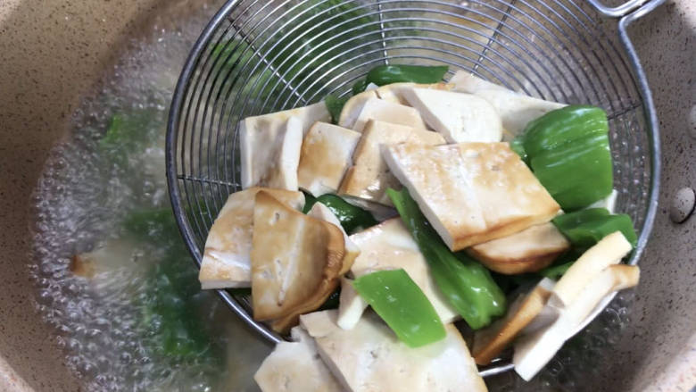 麻辣熏豆干,放入青椒,拌匀煮沸至变色,捞出备用
