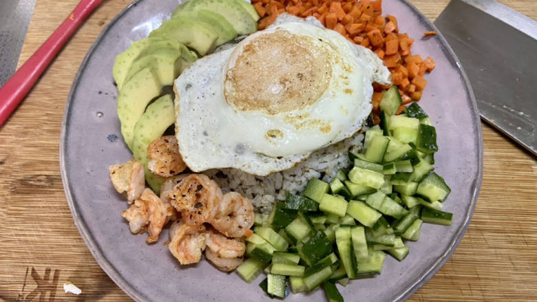 牛油果拌饭,米饭上摆上鸡蛋,围着米饭摆上牛油果,虾仁,黄瓜粒,胡萝卜粒