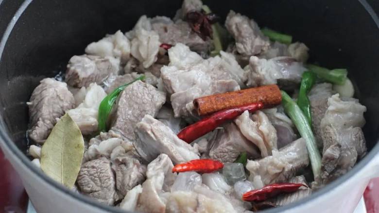 红烧羊肉煲,接着放入羊肉翻炒变色,下红干椒、桂皮、香叶、八角和冰糖翻炒两分钟。
