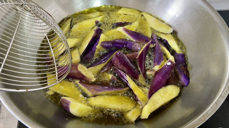 鱼香茄子盖饭,升高油温,大火下茄子,复炸十几秒,吐出多余油脂,沥油盛出