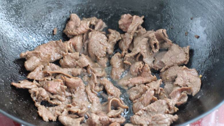 滑蛋牛肉,把牛肉中的食用油沥出倒回锅中,牛肉片铺到上面开火。