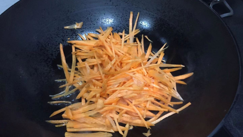 胡萝卜炒茭白丝,下入蒜末炒香,倒入胡萝卜丝