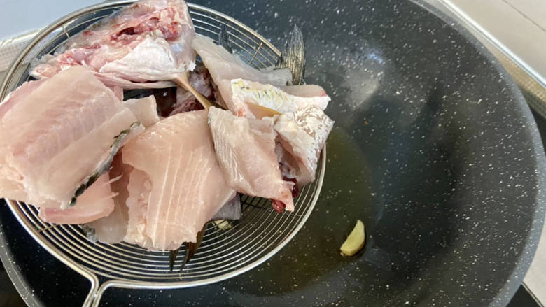 金汤鱼,现在来熬鱼汤,热锅后加入少许食用油,下姜片煸香,下鱼骨,稍微煎制