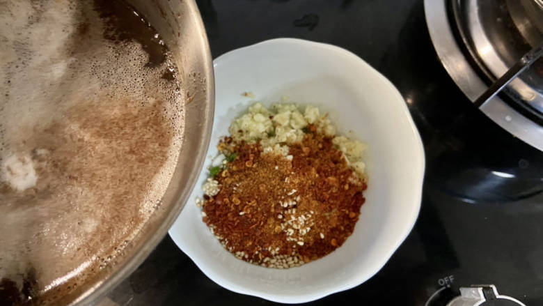凉拌粉丝黄瓜,取耐热的碗,加入蒜末,葱末,小米辣,一汤匙辣椒粉,一汤匙熟白芝麻,分次浇上八成热热油,搅拌均匀