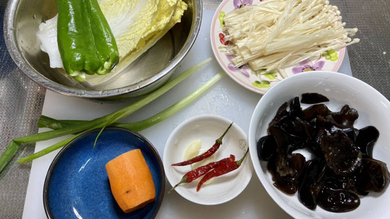 杂炒蔬菜,娃娃菜叶清洗干净,青椒去蒂去籽洗净,金针菇去根洗净撕小朵,泡发好的木耳在流动水下揉搓洗净,胡萝卜削皮洗净,蒜剥皮,小米辣洗净