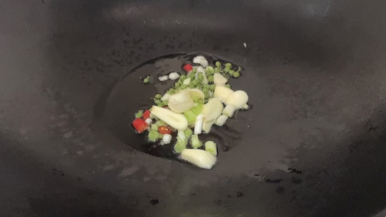 家常鲫鱼,锅中倒入适量油烧热后倒入蒜头,藤椒粒,辣椒末煸出香味