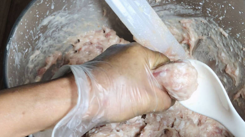 手工肉丸,肉馅打发好后,用手虎口处将肉馅挤成丸子,用汤勺舀入肉丸