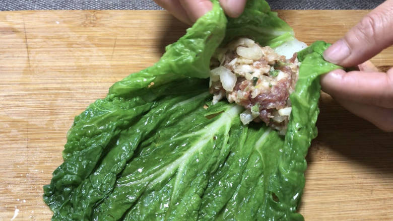 白菜卷肉,摊开,放入备好的肉末,将菜叶两边折起盖住肉末,再卷成卷