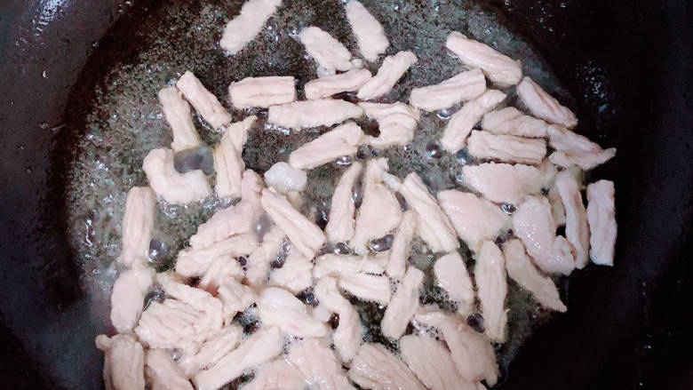 蒜苔香干,锅中倒入油,加热至五成热,放入肉丝翻炒均匀。